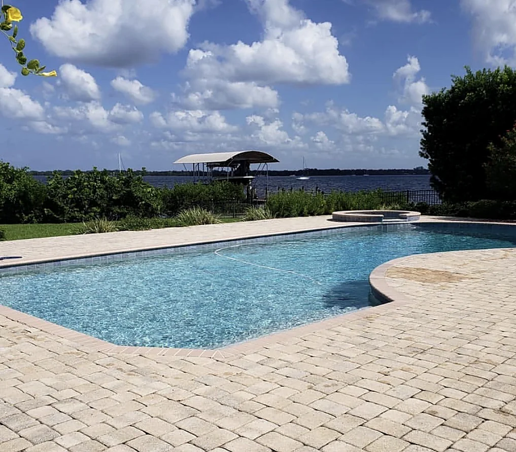 Freeform pool with a paver deck and a spa on the waterfront